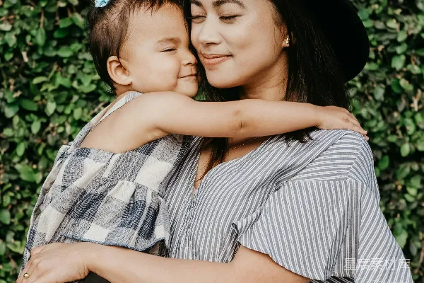 高清摄影 一个女人抱着孩子站在灌木丛旁。