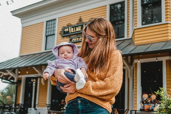 高清摄影 一个抱着婴儿的女人站在一栋建筑前。