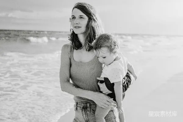 高清摄影 一个人在海滩上抱着一个婴儿。
