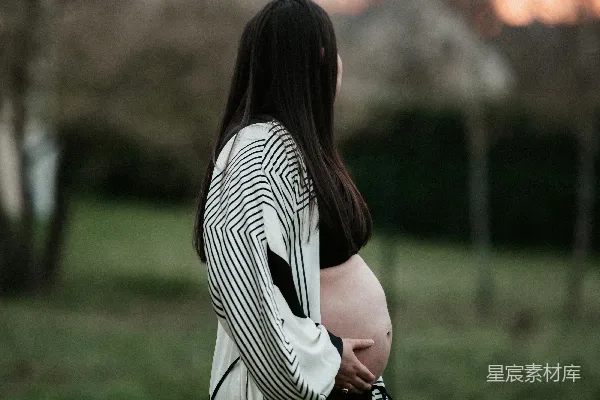 高清摄影 一位孕妇站在夕阳下的田野里。
