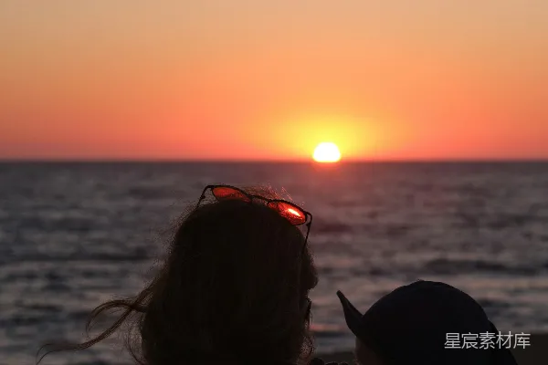 高清摄影 一位女子在夕阳下的海滩上抱着一个孩子。