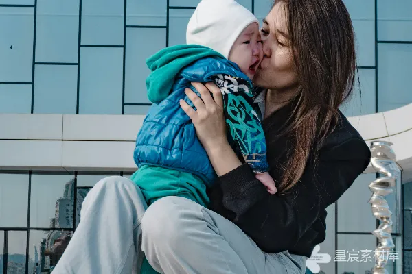 高清摄影 母亲在现代化建筑前亲吻她的婴儿