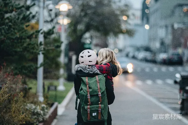 高清摄影 一个女人背着一个孩子走在街上。