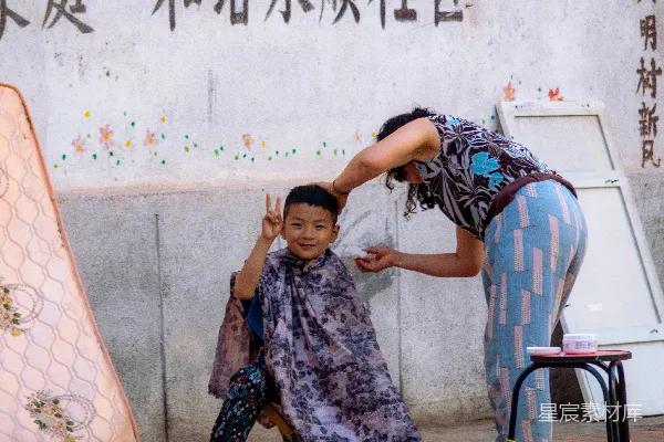 高清摄影 一个男孩坐在凳子上，旁边站着一位女子，她靠近一堵墙。