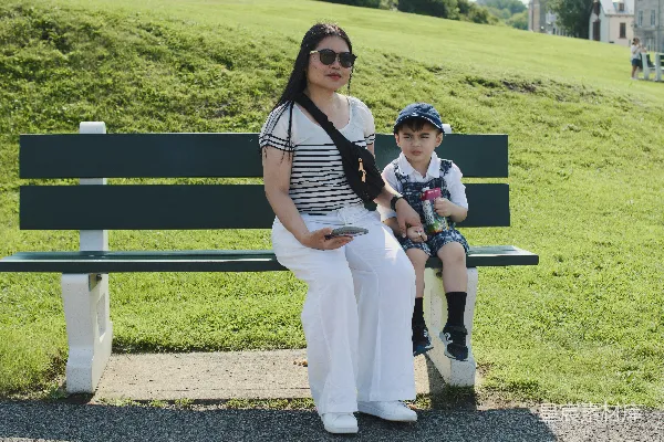 高清摄影 夏天，女人和孩子坐在公园的长椅上。