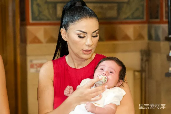 高清摄影 穿着红裙子的女人抱着一个穿白色衣服的婴儿。