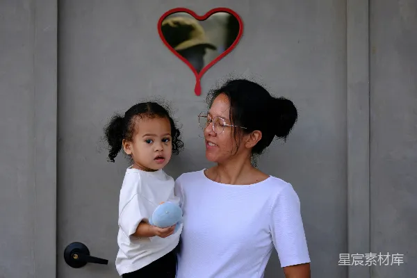 高清摄影 一个女人抱着一个孩子站在一扇门前。