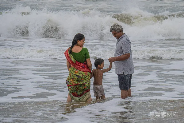 高清摄影 一家人站在海中，海浪拍打着岸边。