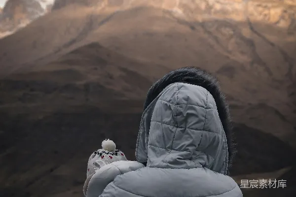 高清摄影 穿灰色泡泡外套的人面对着灰色的山。