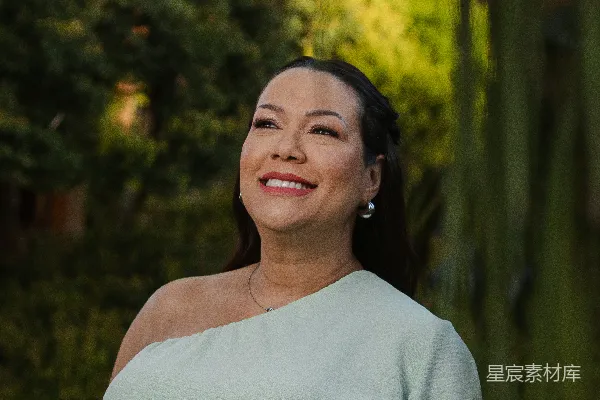 高清摄影 一位穿着浅绿色连衣裙的孕妇在户外微笑着。