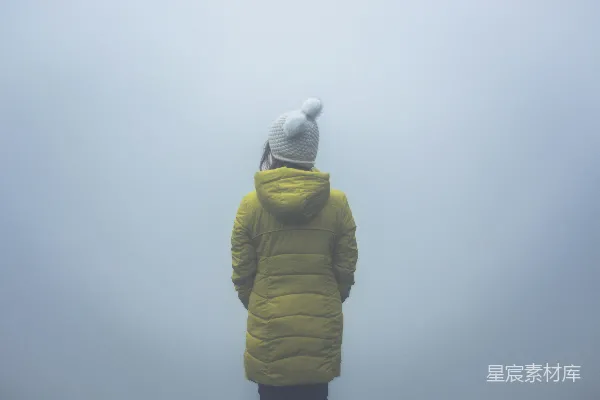 高清摄影 穿绿色连帽夹克的人背对着镜头站着。