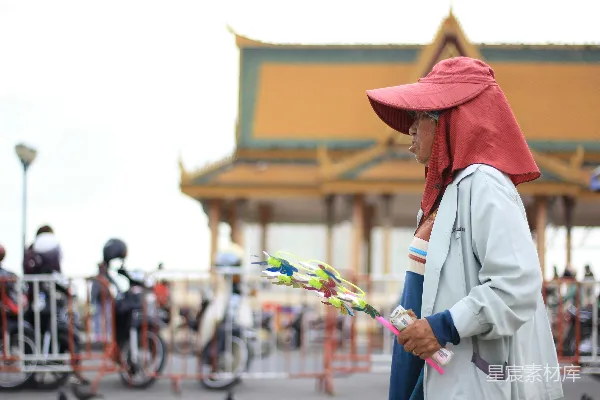 高清摄影 一个穿着白色长袖衬衫和棕色帽子的人，手里拿着一把白色和绿色的塑料伞。