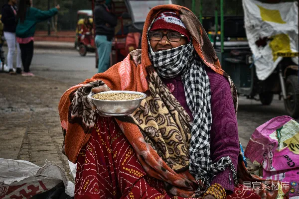 高清摄影 一个女人蹲在地上，手里拿着一碗食物。