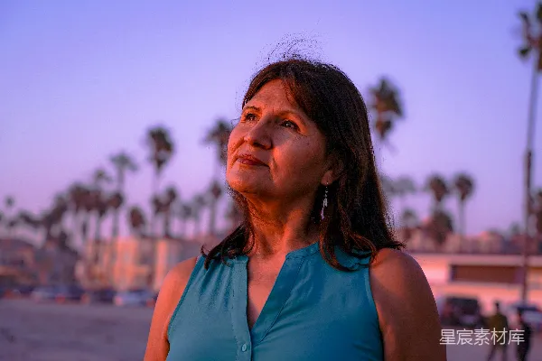 高清摄影 一个穿着蓝色上衣的女人站在海滩上。