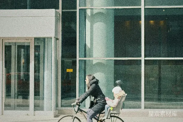 高清摄影 一个男人骑着自行车经过一座高楼。