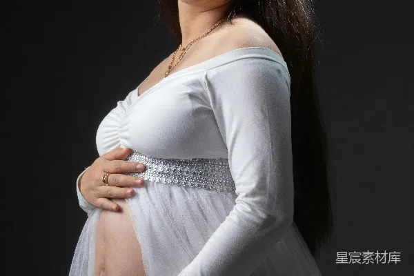 高清摄影 一位孕妇微笑着，穿着一件白色连衣裙。