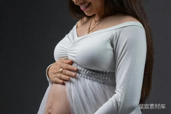 高清摄影 怀孕的女性穿着白色连衣裙摆姿势拍照。