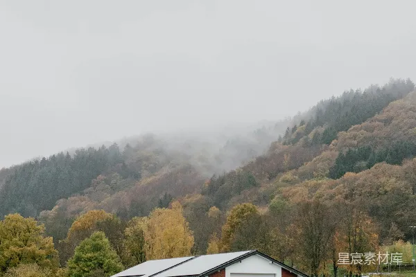 高清摄影 一幢白色建筑位于水边，背景中有树木和山丘。