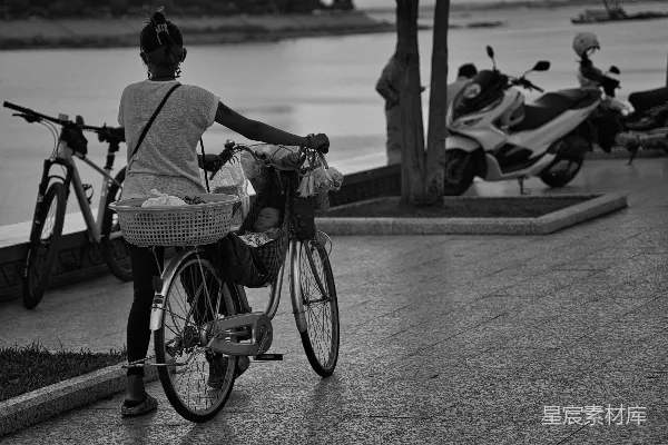 高清摄影 一个女人在水边骑自行车。