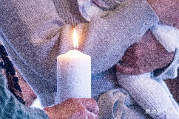 高清摄影 一个女人抱着一个婴儿，手里还拿着一支点燃的蜡烛。