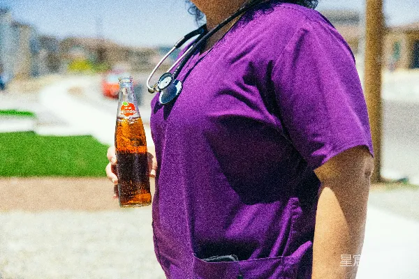 高清摄影 一个戴着听诊器的女人手里拿着一瓶啤酒。