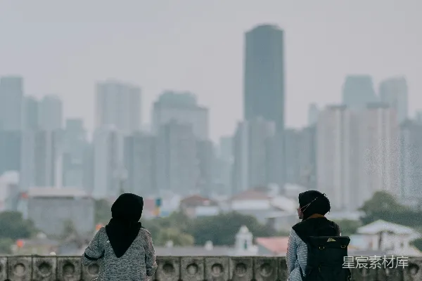 高清摄影 两个人坐在长椅上，背景是城市。
