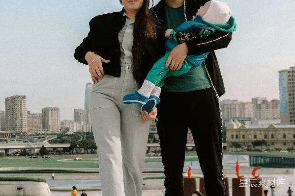 高清摄影 一对夫妇抱着一个婴儿，背景是城市景观。