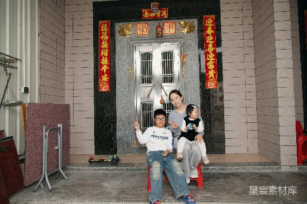 高清摄影 一个带着两个孩子的母亲站在一栋建筑前。