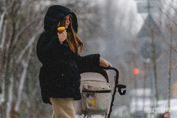 高清摄影 一个女人推着婴儿车走在积雪覆盖的街道上