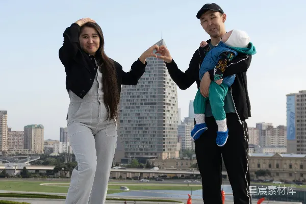 高清摄影 一对带着婴儿的情侣在屋顶俯瞰城市。