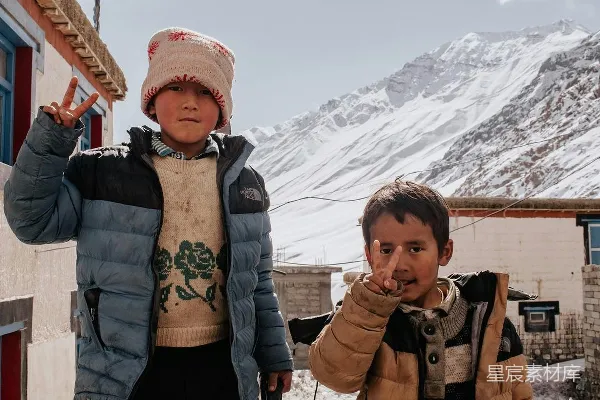 几个男孩在皑皑白雪覆盖的山顶前摆姿势拍照。