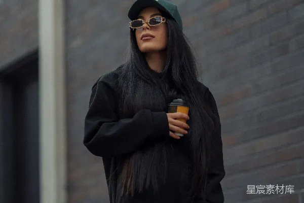 一个长发黑色的女人穿着黑色的运动衫和黑色的裤子。