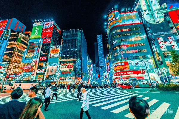 高清摄影 人们在夜间穿过建筑物附近的行人道。