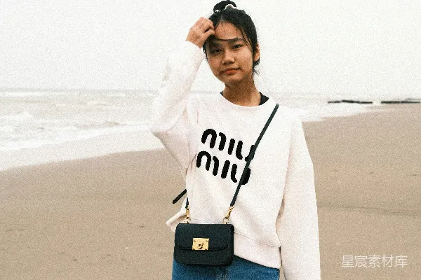 一个女人站在海滩上，旁边是海洋。