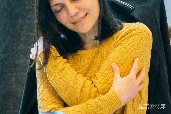一个女人坐在一张桌子旁，旁边有一台笔记本电脑。