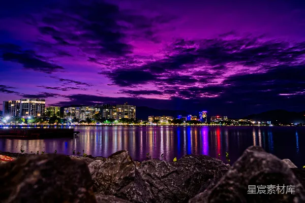 高清摄影 灰色的海岸岩石，在夜景中可以看到城市的天际线。