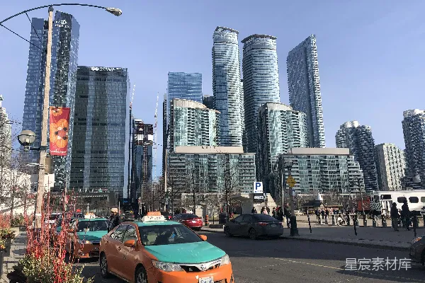 高清摄影 白天，城市建筑附近路上的一辆橙色汽车。