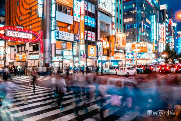 高清摄影 夜景中的城市景观，人行道上的行人模糊不清，而广告牌则显得格外明亮。