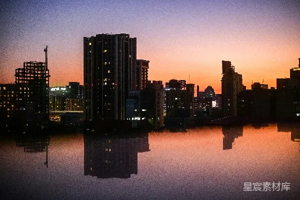 高清摄影 夕阳下的城市景象，水中倒映出城市的轮廓。