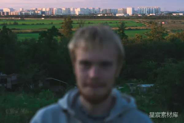 一个男人站在一片空地上，背景是城市。