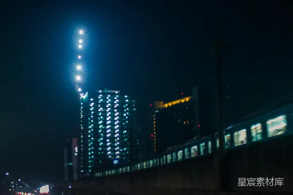 高清摄影 夜间，火车经过灯火通明的城市建筑旁