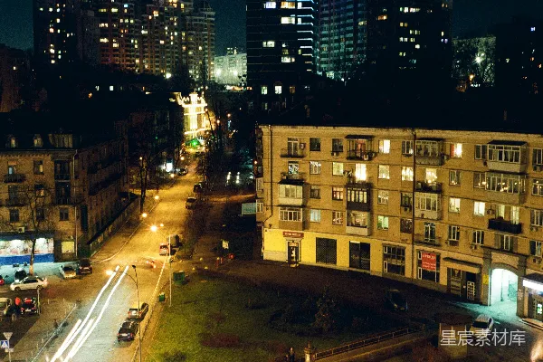 高清摄影 夜间，高楼大厦之间路边停着的汽车。