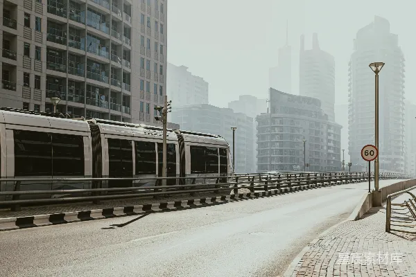 高清摄影 一列火车沿着高大建筑旁的轨道行驶