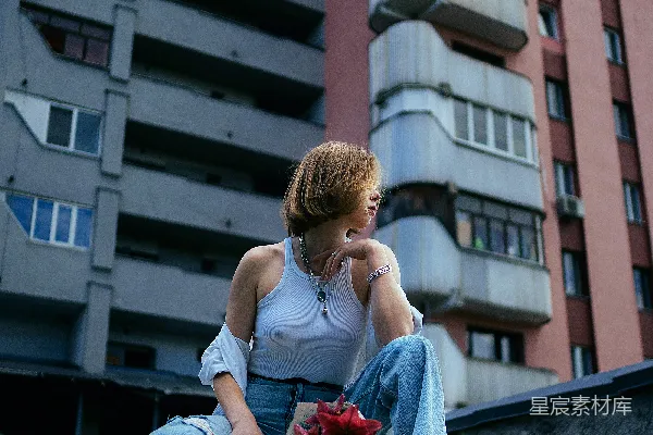 一个女人坐在一栋高楼前的窗台上。