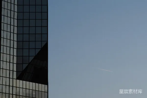 高清摄影 一架飞机在天空中飞过一座高楼旁边