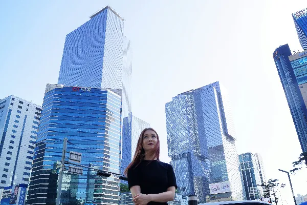 高清摄影 穿着黑色衬衫的女人站在白天的高楼旁边。