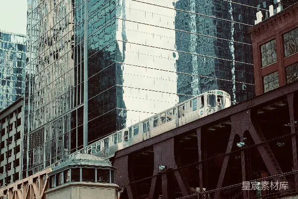 高清摄影 一列火车在高大的建筑物旁的一座桥上行驶。