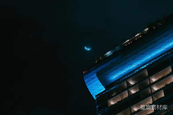 高清摄影 夜晚的建筑物在月光下显得格外明亮，挂着一轮新月。