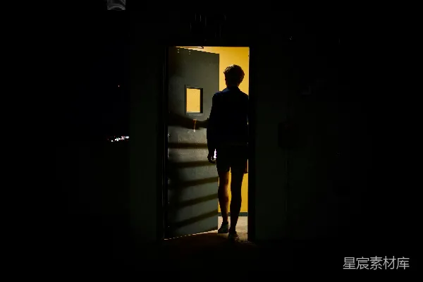 高清摄影 穿黑色夹克的男人站在一扇白色木门前。