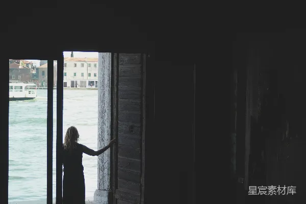 高清摄影 穿着黑色连衣裙的女人站在窗边。